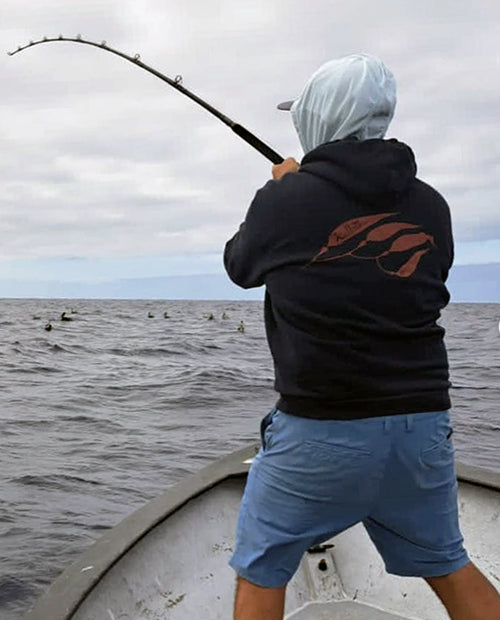 Person fishing on a boat with a cloudy sky and ocean background