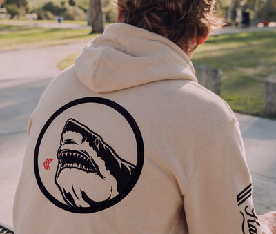 Lifestyle view of person wearing the beige Great White Shark hoodie outdoors, showing back graphic detail